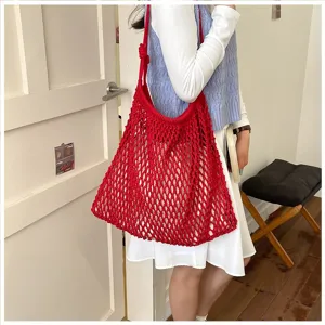 Grand sac cabas rouge en maille crochetée porté par un mannequin dans un cadre élégant