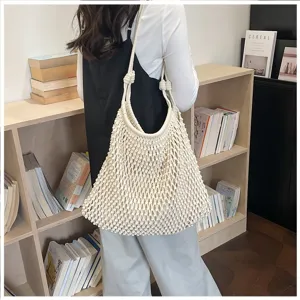 Détail d'un sac cabas en macramé tissé crème avec bandoulières élégantes sur une personne