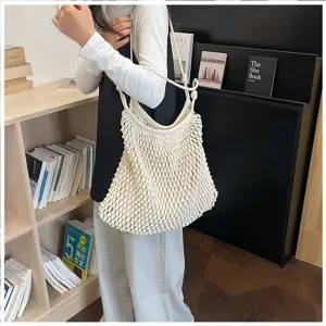 Modèle portant un grand sac à bandoulière en maille tissée blanche pour les vacances