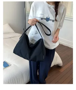 Lifestyle-Foto einer minimalistischen großen schwarzen Nylon-Umhängetasche in einem Schlafzimmer