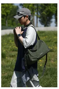 Vue extérieure d'un sac à bandoulière vert olive à carreaux sur un mannequin homme