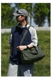 Grand sac à bandoulière en tissu Oxford à carreaux verts porté dans un cadre de vie extérieur