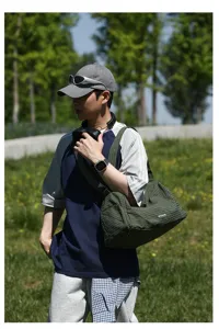 Vue de côté d'un grand sac bandoulière Oxford à carreaux verts porté par un mannequin