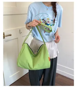 Nahaufnahme eines Modells mit einer grünen wasserdichten Nylon-Hobo-Tasche für den Alltag