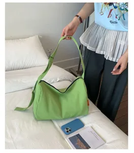 Detailansicht einer grünen wasserdichten Nylon-Umhängetasche, die auf einem Bett liegt