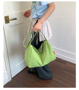 Große wasserdichte Nylon-Schultertasche in Limettengrün, gehalten von einem Model in hellem Raum