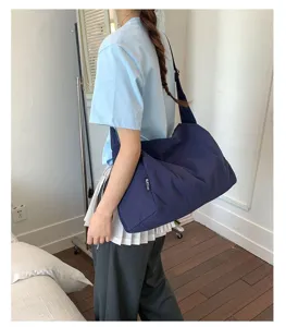Detailansicht einer dunkelblauen wasserdichten Nylon-Umhängetasche mit Label am Modell