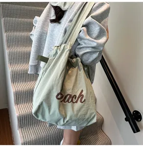 Primer plano de un bolso tote de nailon verde claro con estampado 'Beach' en modelo