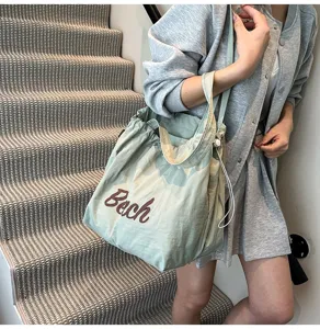 Bolso tote verde menta con estampado 'Beach' llevado por una modelo en la escalera