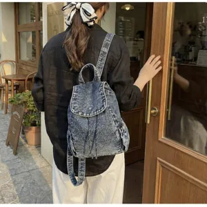 Macro detail of retro washed blue denim backpack featuring drawstring and flap closure