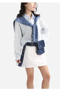 Vue détaillée de la ceinture en jean élégante et de sa mini sacoche, boucle métal et lanière.
