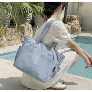 Lifestyle-Ansicht einer minimalistischen großen blauen Segeltuchtasche an einem Pool