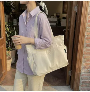 Frau trägt eine große beige Segeltuchtasche in einer entspannten Umgebung im Freien