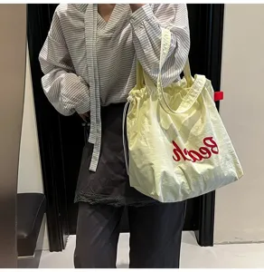 Primer plano de un bolso tote crema de gran capacidad con bordado rojo Beach en estilo informal