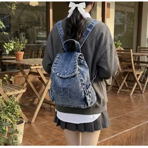 Rear view of a stylish vintage washed denim drawstring backpack shown on a model outdoors