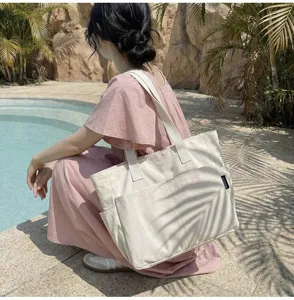Geräumige cremefarbene Canvas-Tragetasche, von einem Model in Poolnähe präsentiert