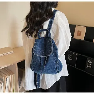 Vintage blue denim backpack with drawstring closure shown on a model in a bookstore setting