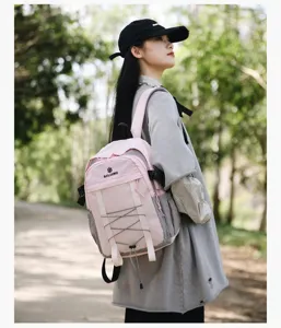 Modelo asiática con una mochila de exterior rosa y gris en un entorno forestal.