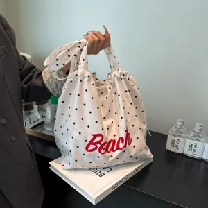 Primer plano del estampado rojo Beach en un bolso tote de tela blanca con lunares