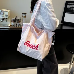 Vista detallada del bolso tote casual rosa con bordado Beach rojo usado por una modelo