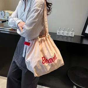 Primer plano del tejido drapeado y el estampado Beach rojo del bolso tote con cordón