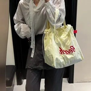 Foto de modelo casual de una bolsa tote grande amarillo claro con letras Beach rojas