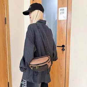 Λεπτομερής προβολή καφέ καρό τσάντας techwear που φοριέται από ένα μοντέλο