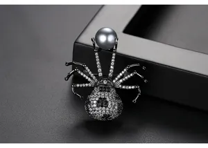 Nahaufnahme einer schwarzen Spinnenbrosche mit Zirkonia-Besatz und einer runden grauen Perle.