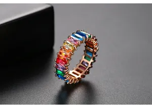 Detalle de cerca de un anillo de eternidad dorado con circonitas de colores talla baguette arcoíris