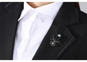 Detailansicht einer Kristall-Spinne-Brosche mit grauer Perle auf einem schwarzen Revers.