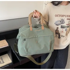 Large green travel bag with embroidered butterfly patterns and adjustable shoulder strap