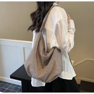 Lifestyle shot of a woman carrying a large brown checkered nylon canvas tote bag