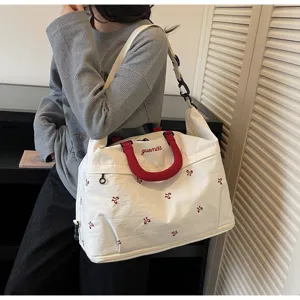 Large white nylon travel bag with red handles and small patterns shown on model shoulder