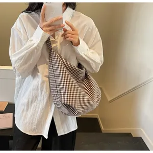 Casual lifestyle photo of a model wearing a large capacity checkered canvas shoulder bag.