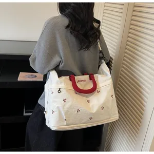 Large white travel tote bag with red handles and flower embroidery worn by model