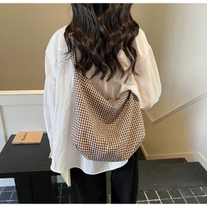 Back view of a woman carrying a casual brown gingham canvas tote bag over her shoulder
