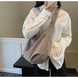 Close-up of a brown gingham checkered canvas crossbody bag worn by a model.
