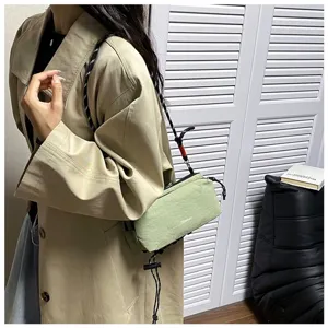 Detailansicht einer hellgrünen Outdoor-Umhängetasche, kombiniert mit einem Trenchcoat.
