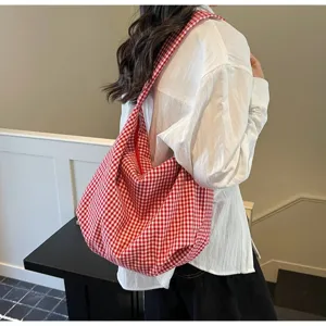 Side detail of large red gingham checkered nylon tote bag worn on model shoulder