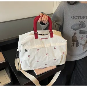 Close-up of stylish large white travel duffel bag with red handles and embroidery