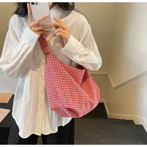 Detailed macro shot of a stylish red and white gingham nylon tote bag worn by a female model