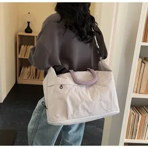 Large stylish lilac travel bag with floral embroidery and shoulder strap shown in use