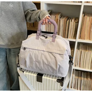 Detailed macro view of a stylish lilac travel bag with delicate embroidery on a white suitcase