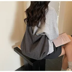 Detailed view of a large checkered nylon tote bag worn by a woman in a casual setting