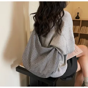 Back view detail of large black and white checked canvas tote bag worn by a model
