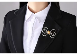 Detailed view of elegant bow brooch with golden pearl on a black blazer lapel.