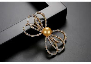 Detailed close-up of an elegant golden bow brooch featuring a shell pearl and crystals