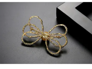 Detailed back view of a golden filigree bow brooch featuring a central shell pearl.