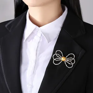 Elegant bow brooch featuring a golden shell pearl and crystals on a black suit lapel