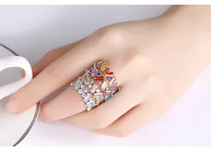 Detailopname van een kleurrijke regenboog zirkoon ring met baguette stenen op een vinger.